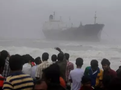 Onlookers gather on the beach after the oil tanker ship Pratibha Cauvery ran aground off the coast
