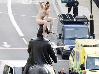Naked man on top of the statue of Prince George