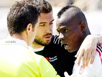 Fiorentina's Viviano embraces AC Milan's Balotelli who is arguing with assistant referee Doveri in Florence