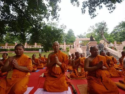 Buddhist monks from Thailand offer prayers while armed Indian security personnel stand guard in the background at the Mahabodhi temple complex in Bodh Gaya