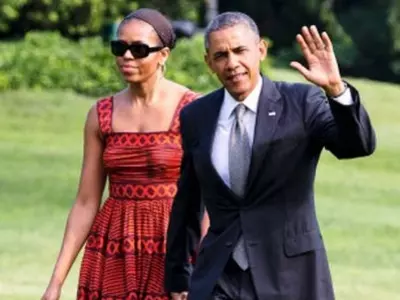 President Barack Obama waves as he walks with first lady Michelle Obama