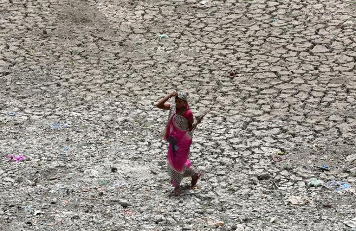 A women carries firewood as she walks through a dried-up portion of the Sabarmati river on a hot summer day in Ahmedabad, India, May 16, 2018.