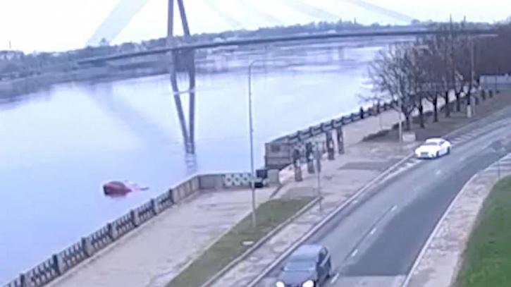 Car rolls across road and into the river. 