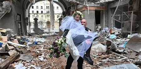 ukraine couple poses in rubble broken car