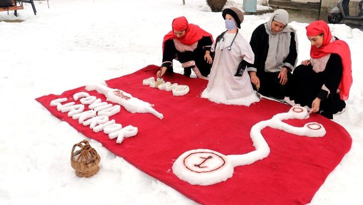 Two sisters do snow sculpture to honor corona warriors.  