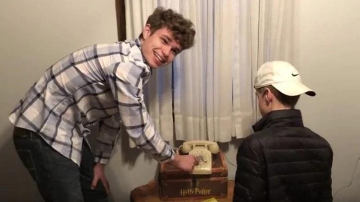Teens try to work out rotary phone. 