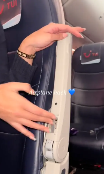 A flight attendant reveals the button to place the armrest in flight