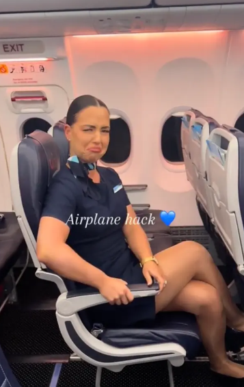 A flight attendant reveals the button to place the armrest in flight