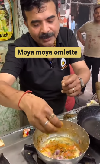 A street food vendor prepares an omelet with crackers and Parle-G cheese