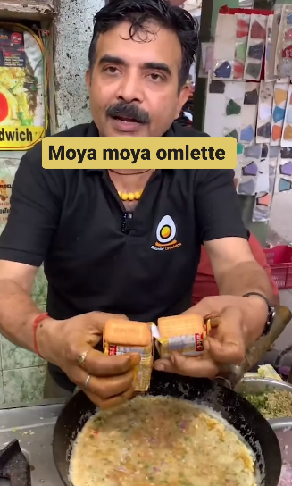 A street food vendor prepares an omelet with crackers and Parle-G cheese