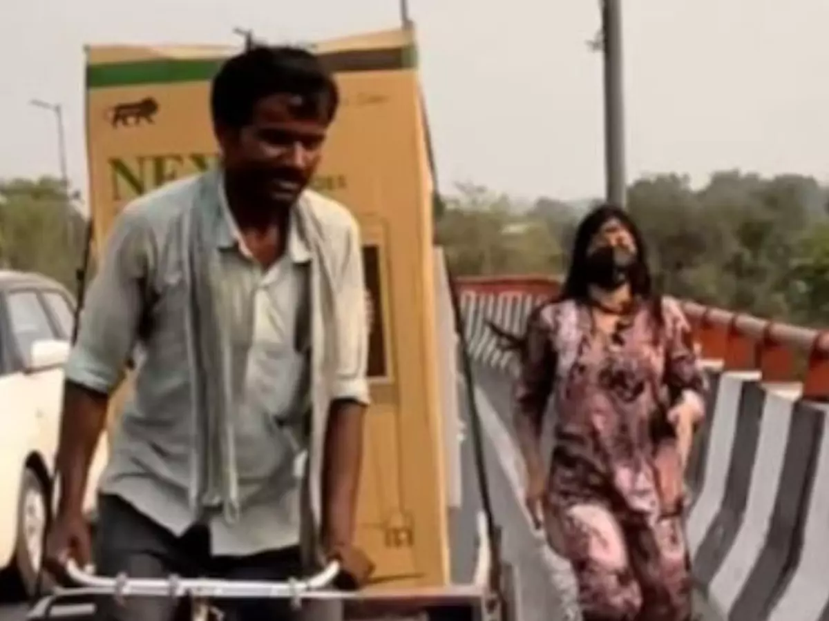 Woman assists rickshaw puller struggling with heavy load on flyover