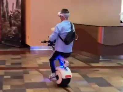 Man Riding E-Vehicle In Mall While Wearing VR Headset