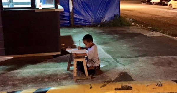 kid doing homework under street light