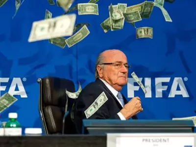 Sepp Blatter has a pile of banknotes thrown over his head by comedian Lee Nelson