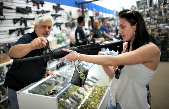 As the U.S. Senate takes up gun legislation in Washington, Dr. Gary Lampert (L), a co-owner of the National Armory gun store, helps Cristiana Verro consider fire arms