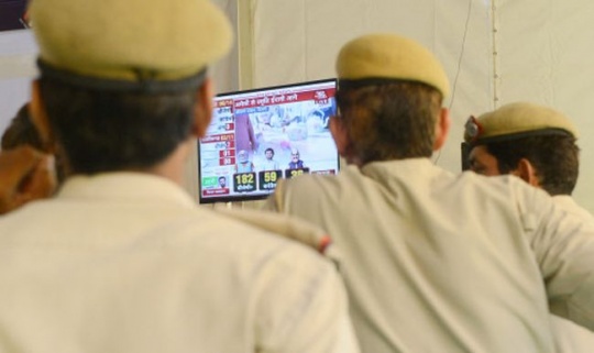 Indian policemen watch election results
