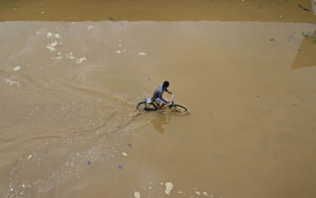 A cyclist pedals through flood water after heavy rain in Dimapur