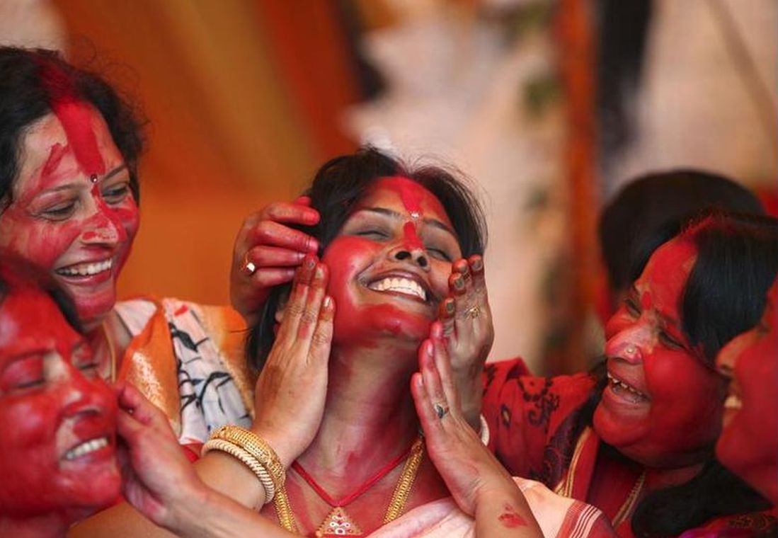 Women apply Sindur on the face of a woman during Durga Puja