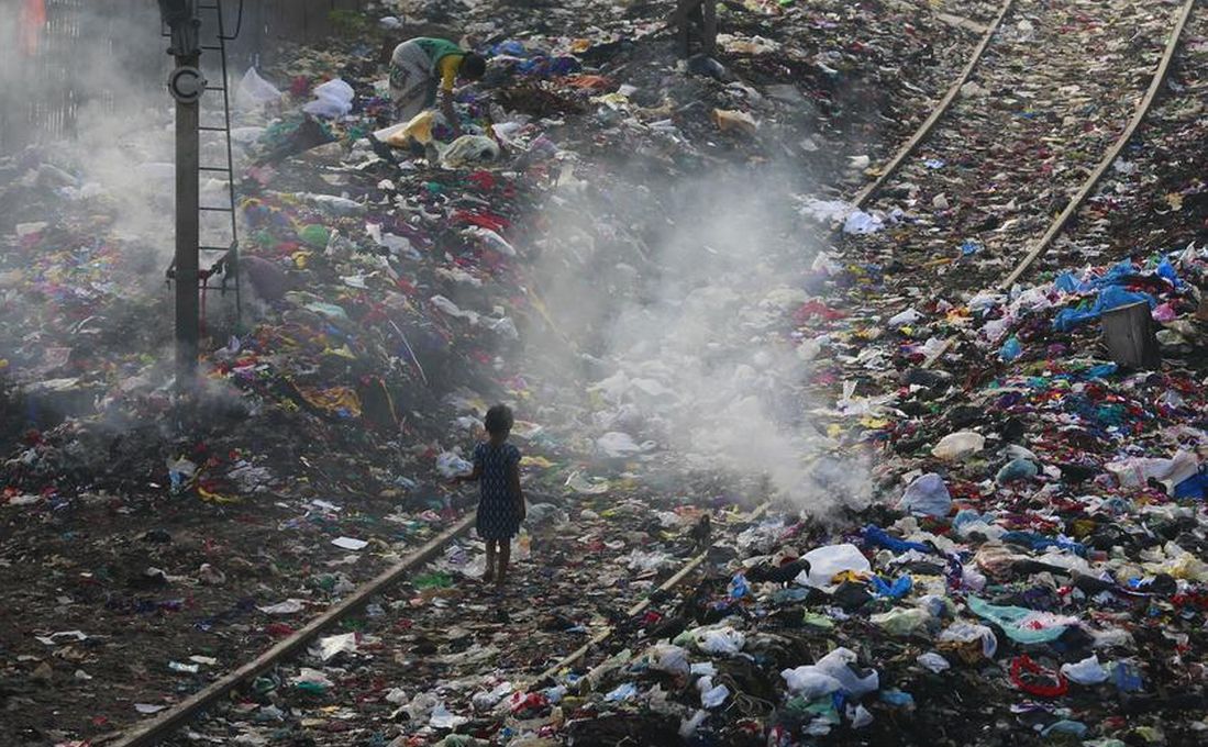 A girl walks on a railway track past piles of dumped garbage in Mumbai