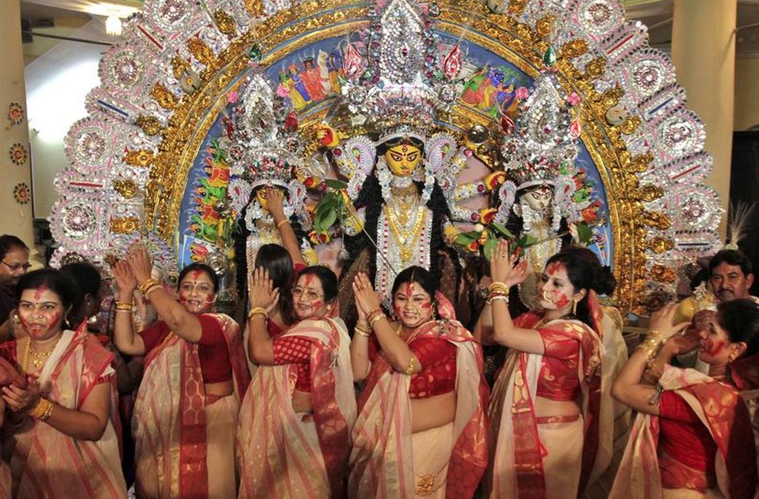 Women perform in front of an idol of goddess Durga 