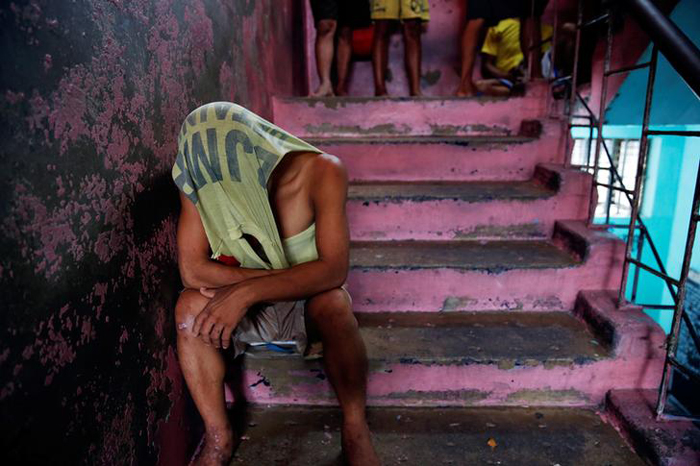 An inmate covers his head as he passes the time inside Quezon City Jail in Manila