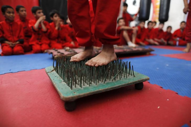 Boy stands on a bed of nails