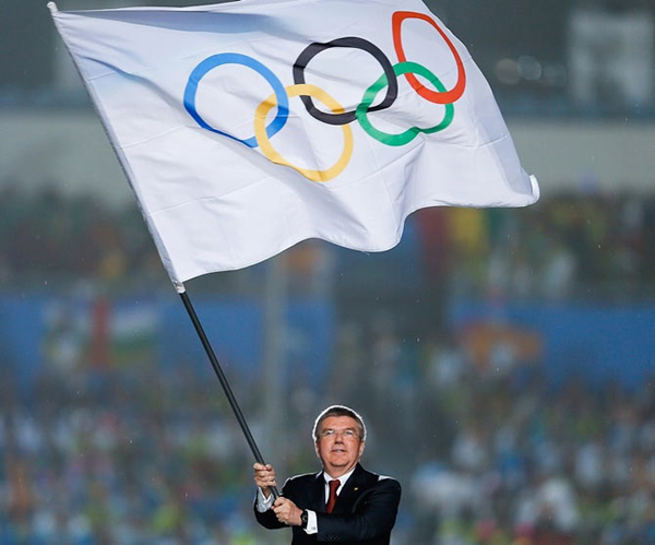 IOC boss Thomas Bach hoisting the Olympics flag
