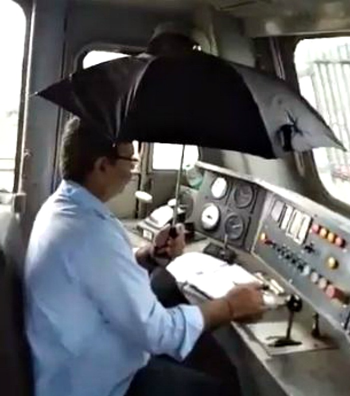 driver holding an umbrella while driving a train