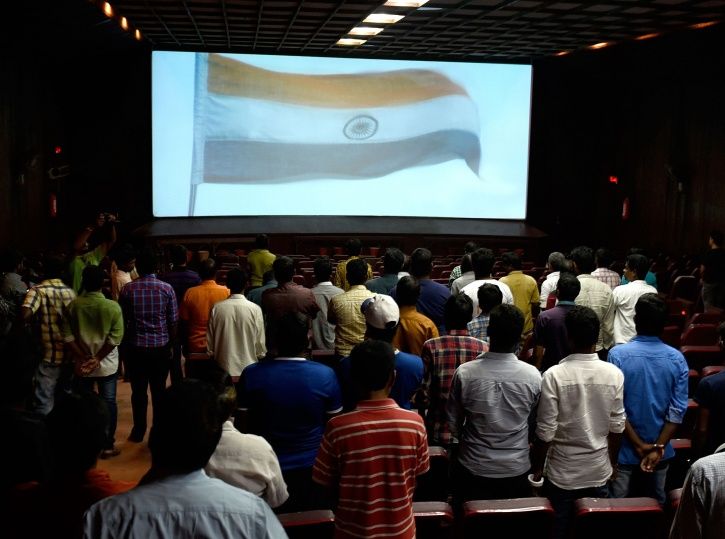 People stand up during national anthem at a theatre.