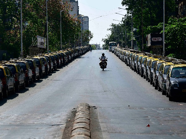 Policemen wearing facemasks ride a motorbike in front of parked Taxis at Mumbai central during a 14-hour long curfew to limit the spreading of coronavirus disease Policemen wearing facemasks ride a motorbike in front of parked Taxis at Mumbai central during a 14-hour long curfew to limit the spreading of coronavirus disease