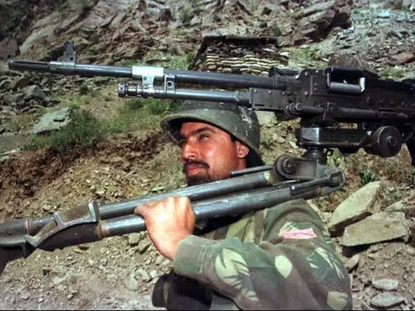 An Indian soldier carries a heavy machine gun towards Tiger Hills in the Drass sector of Indian Kashmir