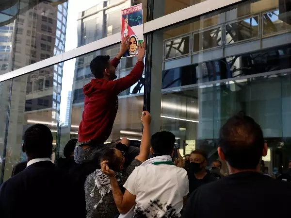 A protester posts a sign reading 'Free Palestine' on the glass wall of the Consulate General of Israel in Chicago during a protest in support of Palestinians