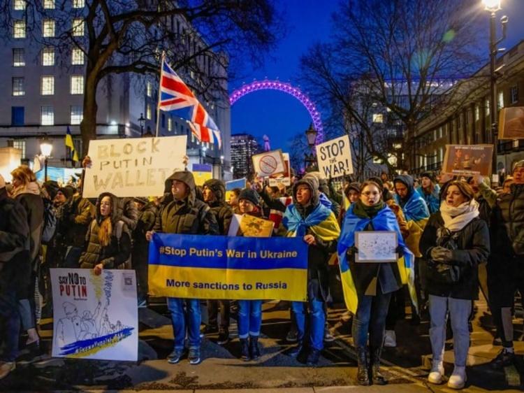 Protesters hold a banner and placards as thousands of Ukrainians and their supporters gather outside Downing Street in London.